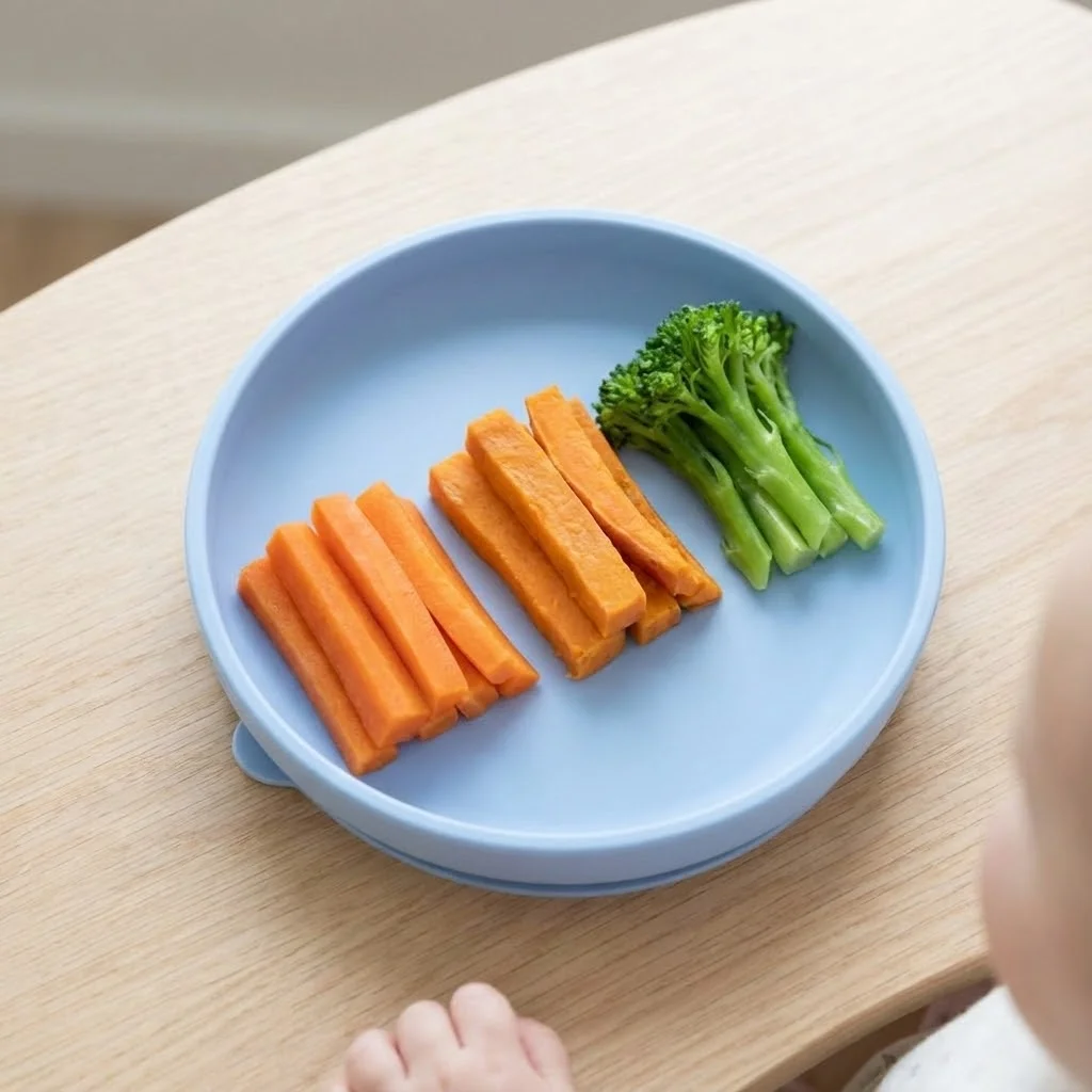 Assiette simple avec trois types de bâtonnets de légumes cuits pour petit de 6 mois, présentation épurée et appétissante