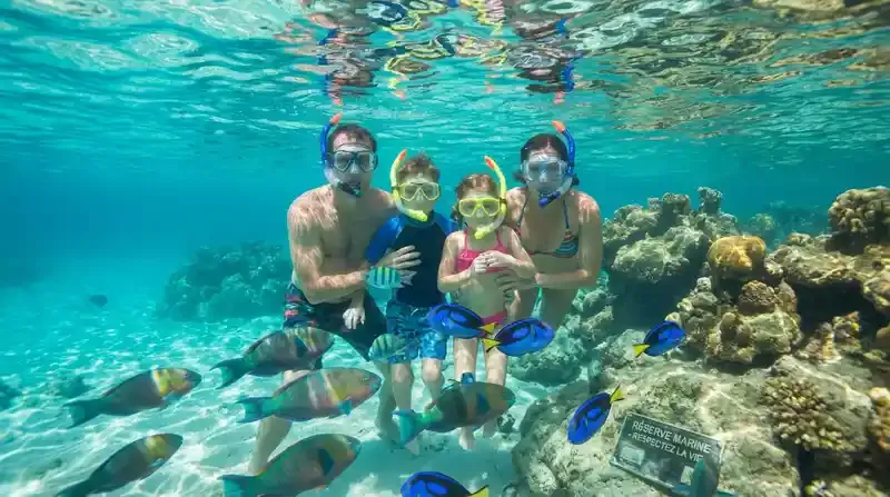 Family snorkeling in turquoise Caribbean waters at Grand Case Beach